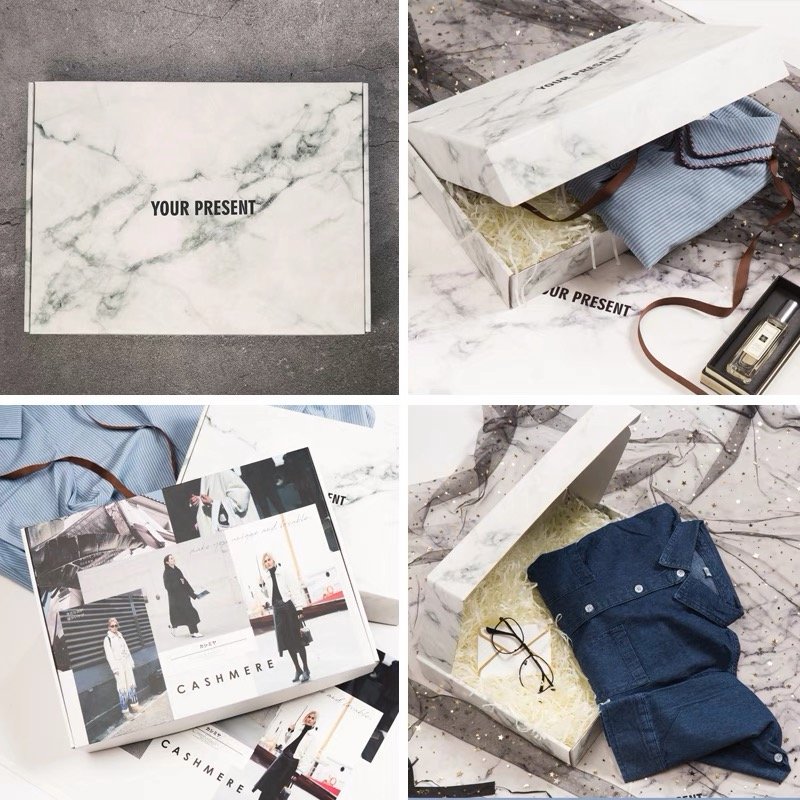 Elegant marble-designed gift box with clothing, magazines, and accessories displayed.