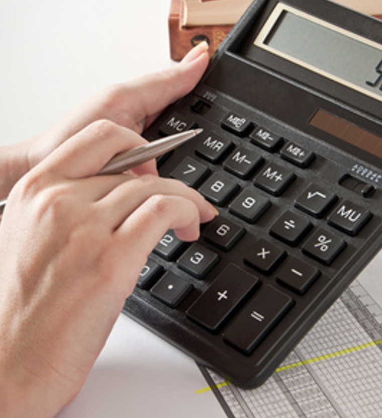 Close-up of hands using a calculator on financial documents.