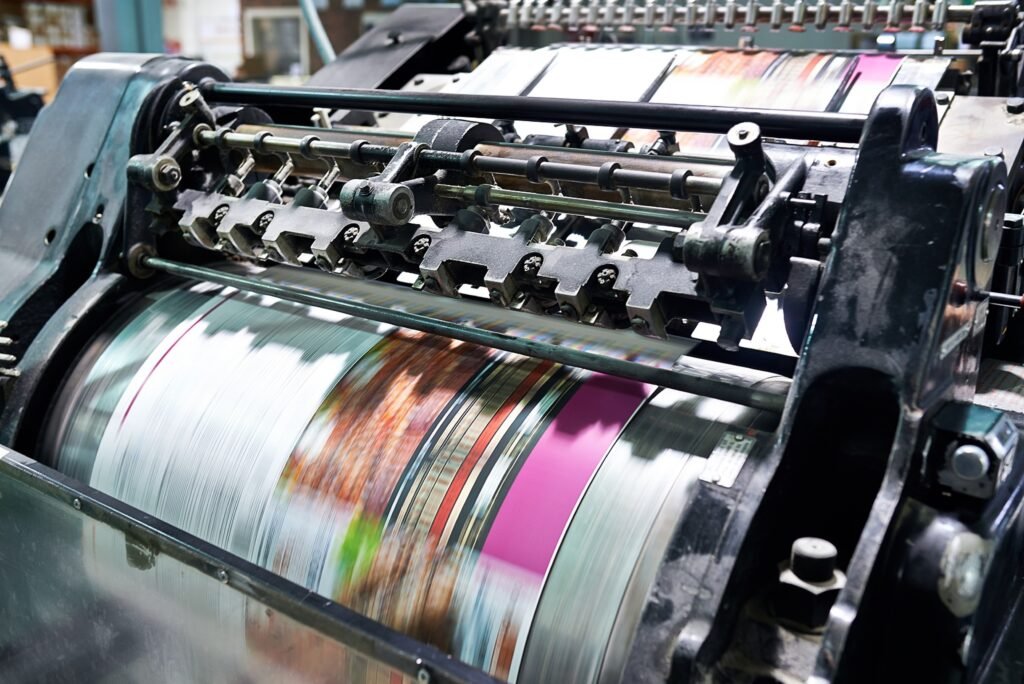 A rotary printing machine in operation, using rotating cylinders to print on continuous rolls of paper or fabric.