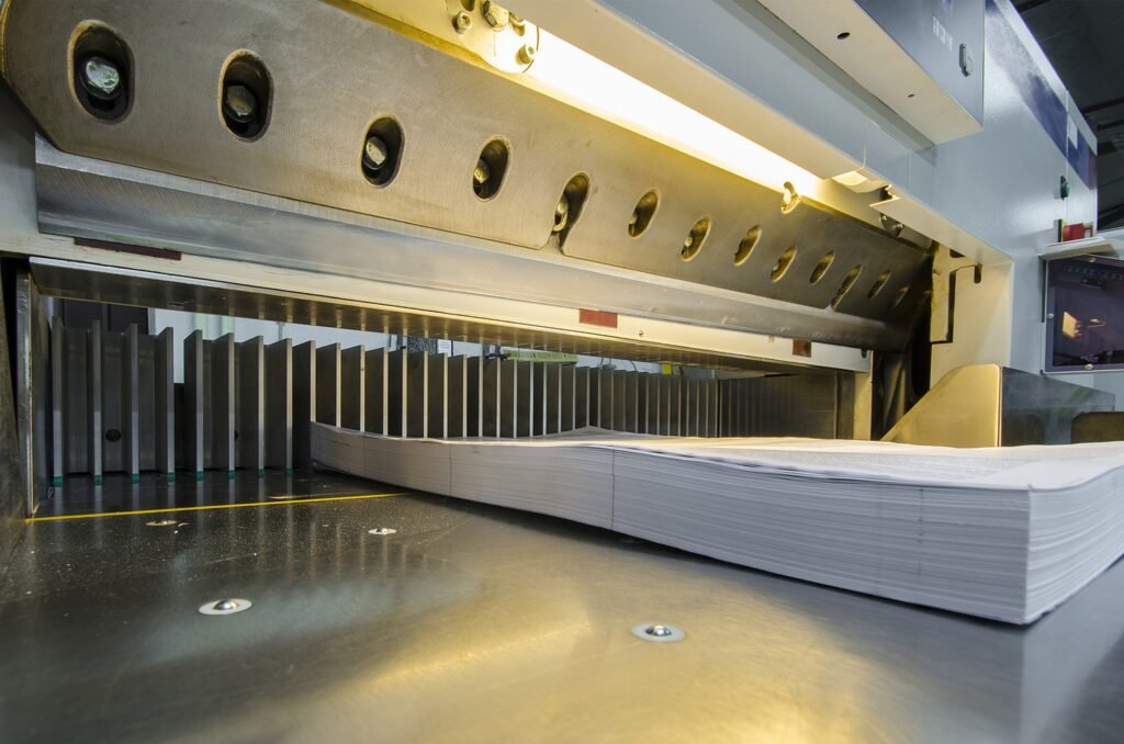A paper cutting machine in operation, precisely cutting large sheets of paper into smaller sizes.