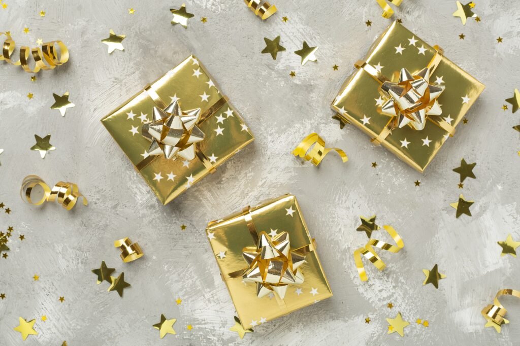 Three golden-wrapped presents with star decorations and curling ribbons on a textured surface.
