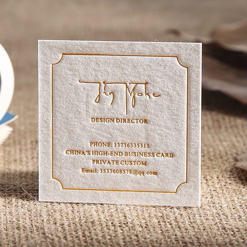 Elegant textured business card with golden embossed text and decorative border.