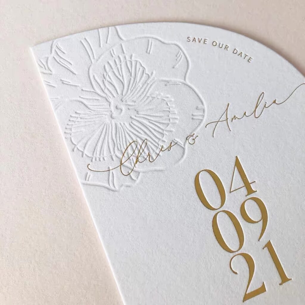 Embossed floral "Save the Date" card with gold details and a wedding date.
