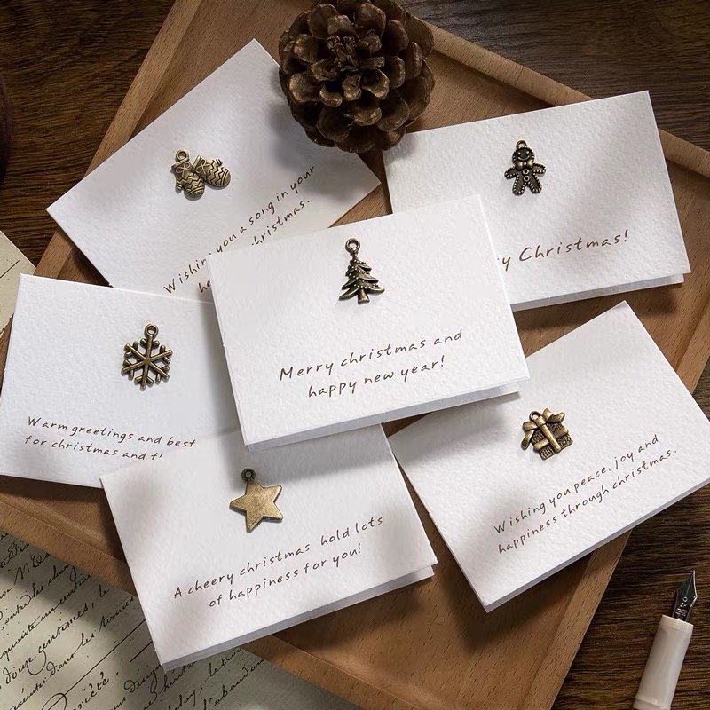 Handcrafted Christmas cards adorned with metallic holiday-themed charms.